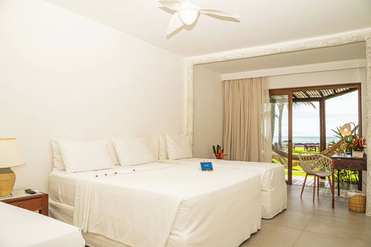 A hotel room with a bed, a desk, a chair, and a view of the ocean.