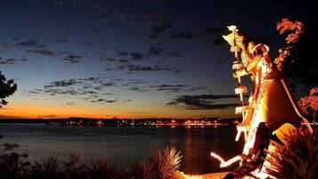 Vista nocturna de un muelle con una estatua iluminada con luces artificiales.