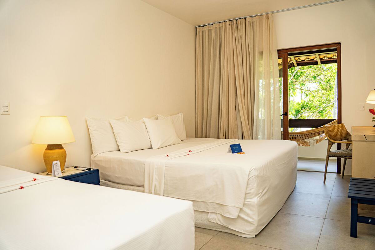A hotel room with a bed, a desk, a chair, and a window with curtains.