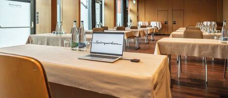 Een vergaderruimte met tafels, laptops en waterflesjes.