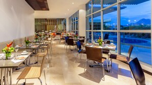 Un comedor moderno con mesas y sillas, ventanas amplias y vistas al exterior.