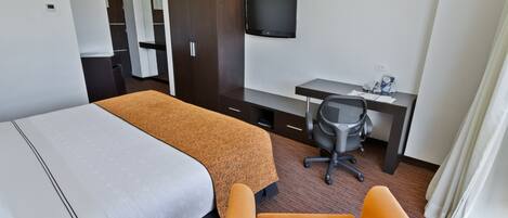 A hotel room with two beds, a desk, a chair, a television, and a wardrobe.