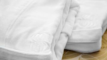 Una toalla blanca doblada con un diseño grabado discreto sobre la cama.