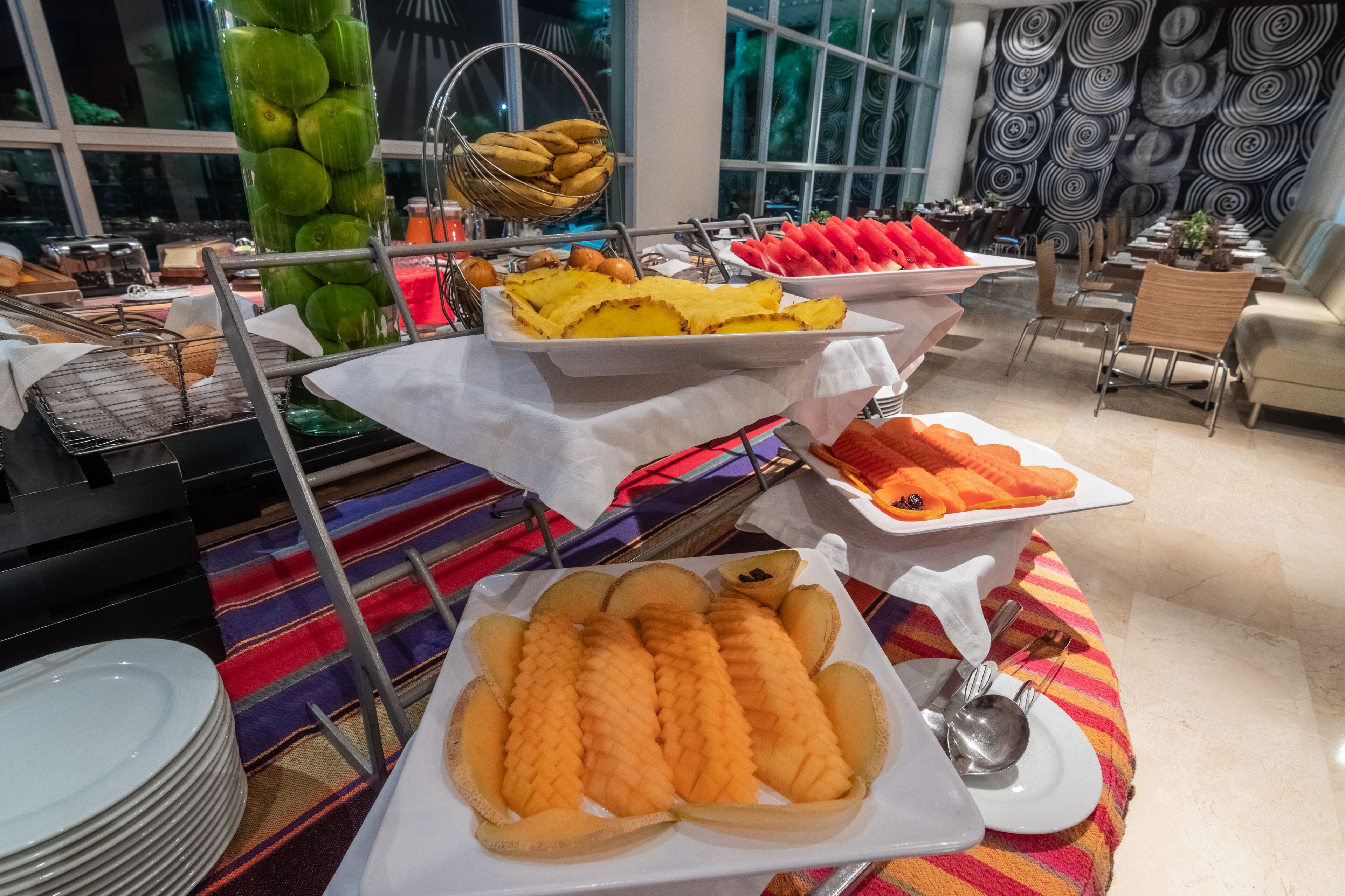Un bufé con diversas frutas y verduras, incluyendo sandía, melón y plátanos.