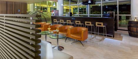 Zona de bar moderna con asientos de cuero, una mesa de vidrio y una barra de madera.