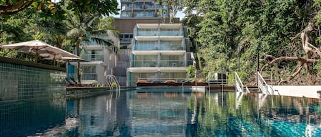 Una piscina al aire libre, sombrillas, sillones reclinables de piscina