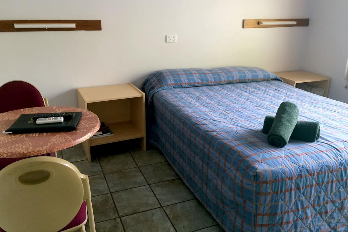 Une petite pièce simple, avec un lit, un bureau et une chaise.