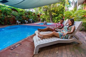 A poolside area with lounge chairs and a small table. - Hotel Kununurra (Kununurra)