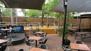 Un área de patio al aire libre con mesas, sillas, un escenario y un letrero que dice Carlton House.