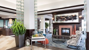 A modern lobby with a fireplace, seating area, and a large potted plant.