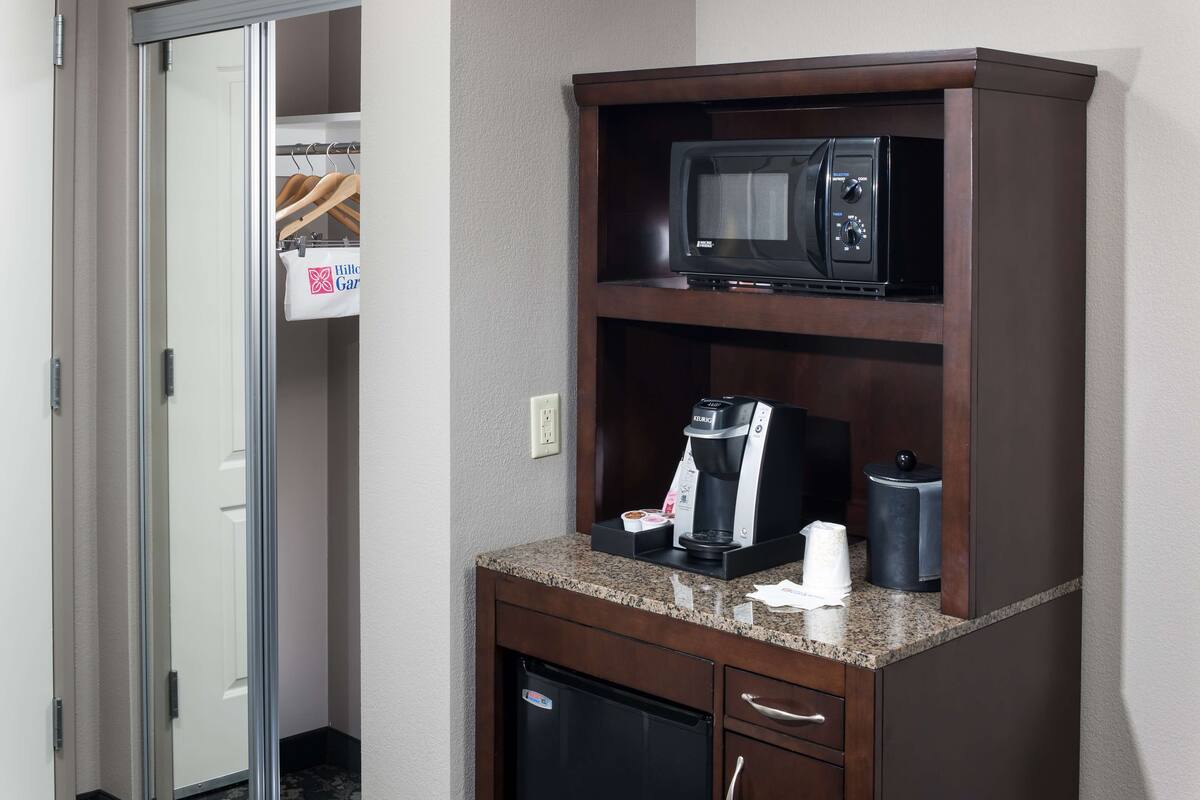 A kitchenette with a microwave, coffee maker, and a small refrigerator.