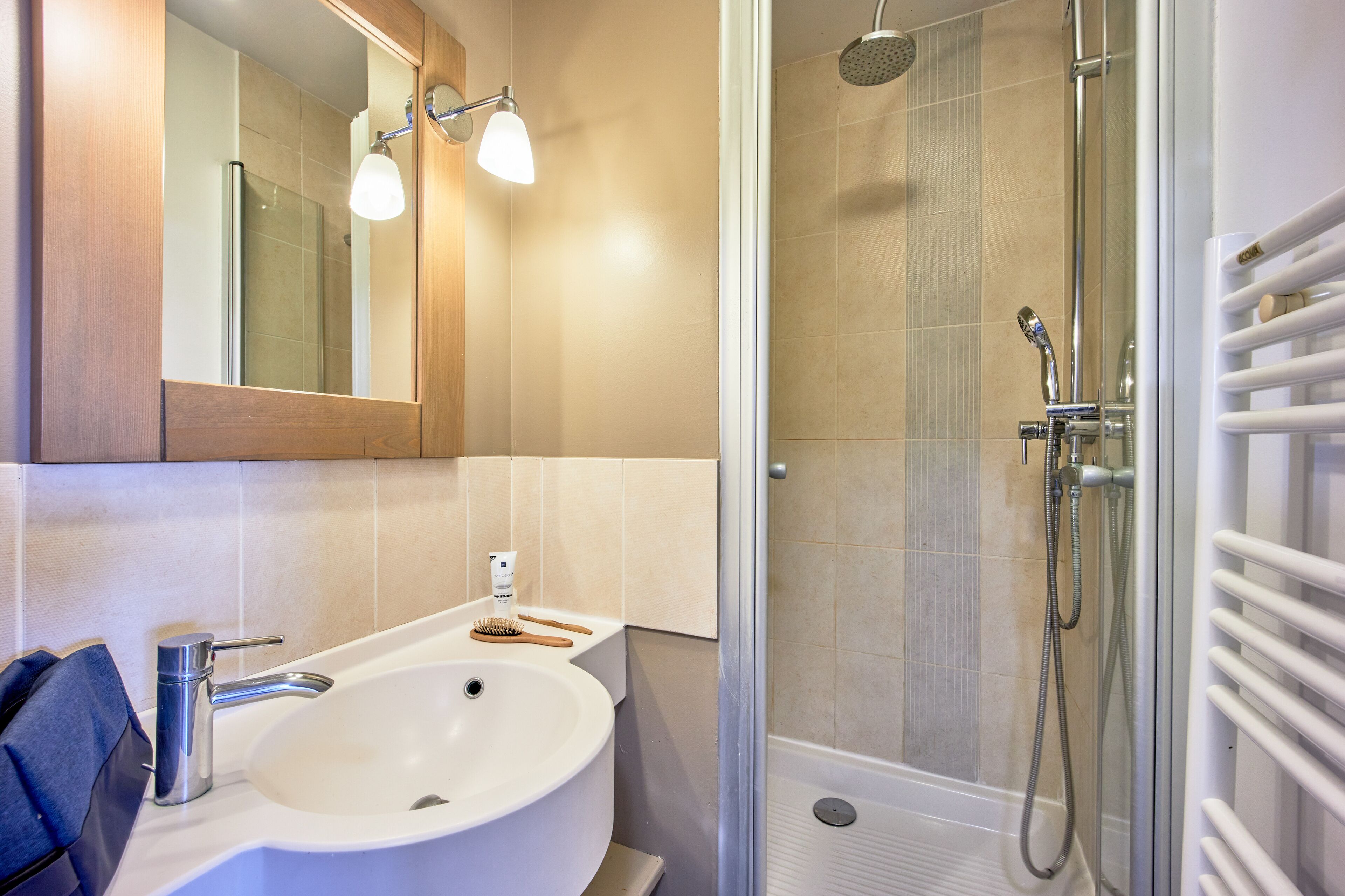 Un bagno con lavandino, specchio, doccia e porta asciugamani.