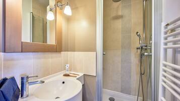 Een badkamer met een wastafel, spiegel, douche en handdoekrek.
