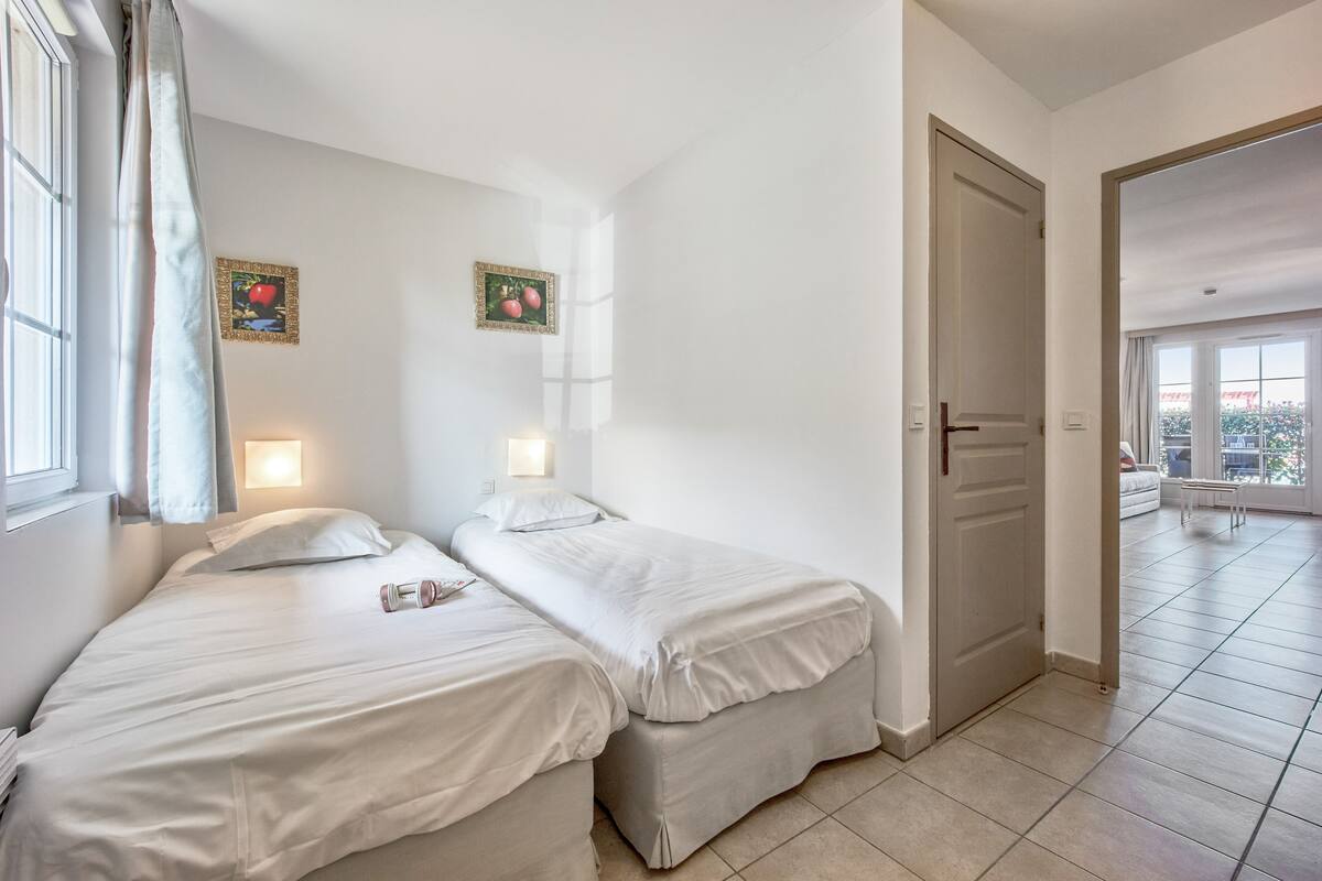 Ein Hotelzimmer mit zwei Betten, einer Tür, die auf einen Balkon führt, und Blick nach draußen.