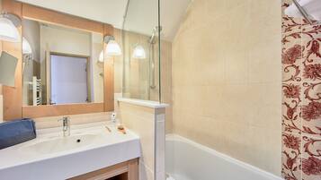 A bathroom with a sink, mirror, and shower.