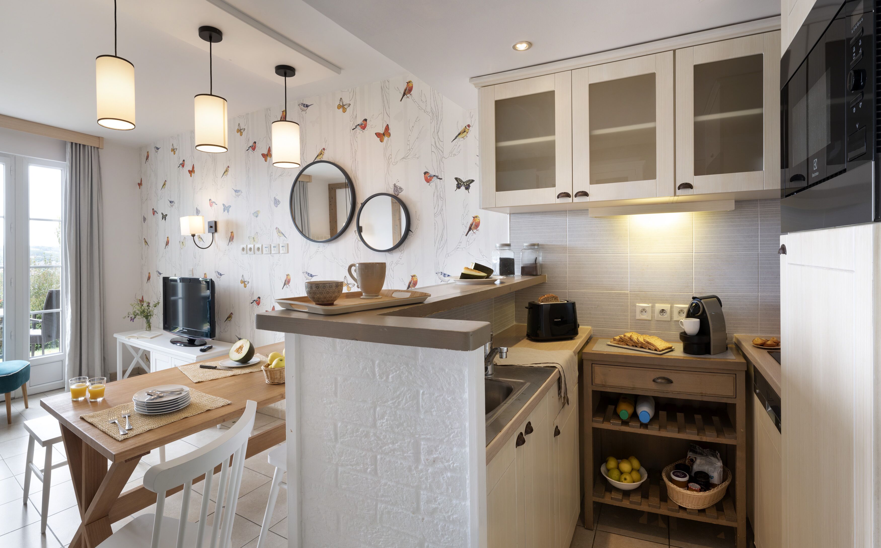 A modern kitchen with white cabinetry, a central island, and a dining area with a table and chairs.