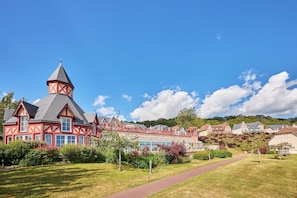 A traditional building with a prominent tower, surrounded by well-maintained gardens and a clear sky. - Résidence Premium & Spa Houlgate - Pierre & Vacances (Houlgate)