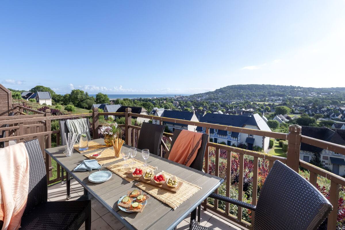 Ein Essbereich mit Tisch für zwei Personen, mit Blick auf eine malerische Stadt- und Hügellandschaft.