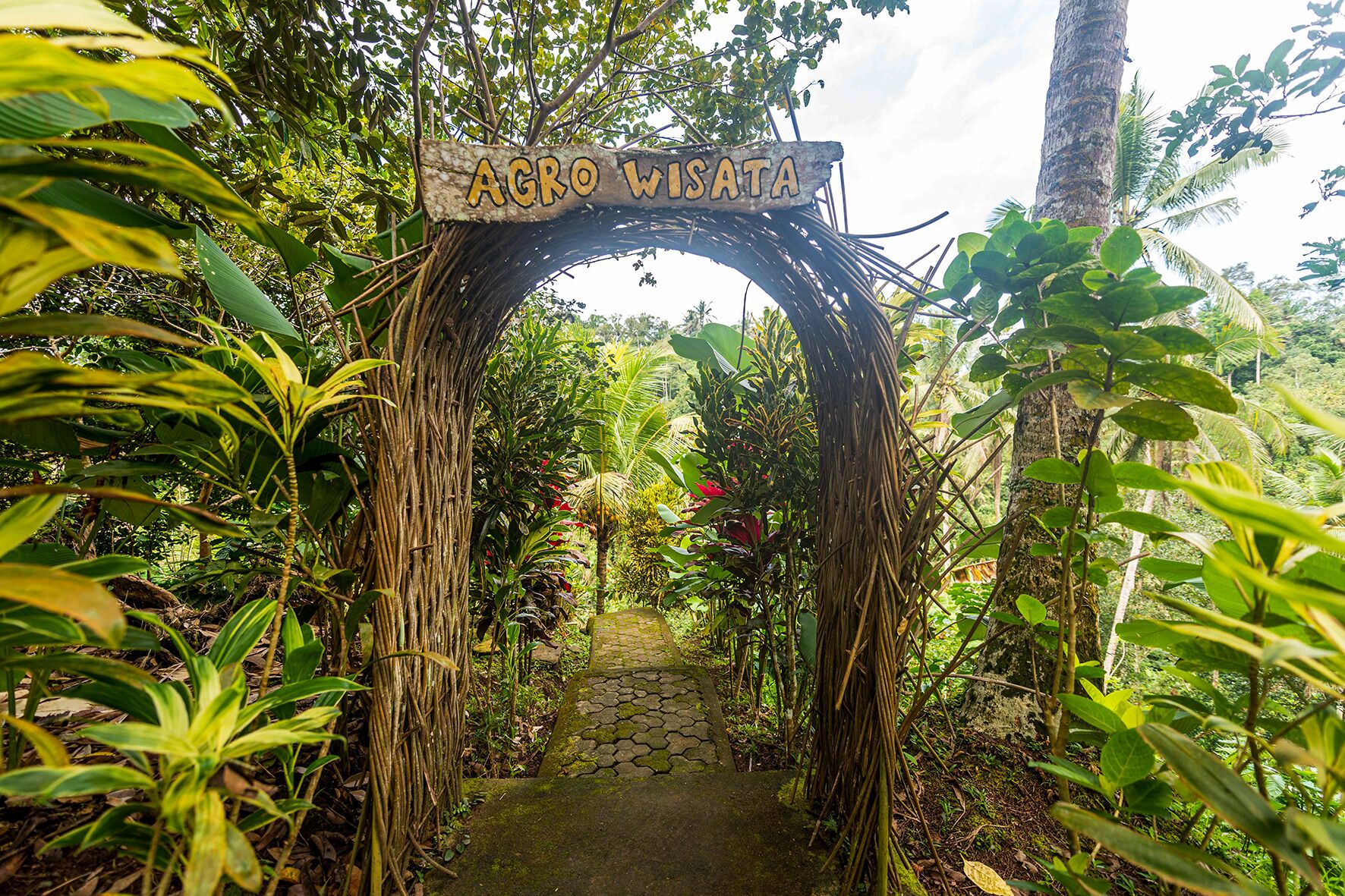 An archway with the inscription 'AGRO WISATA' leading into a lush garden.