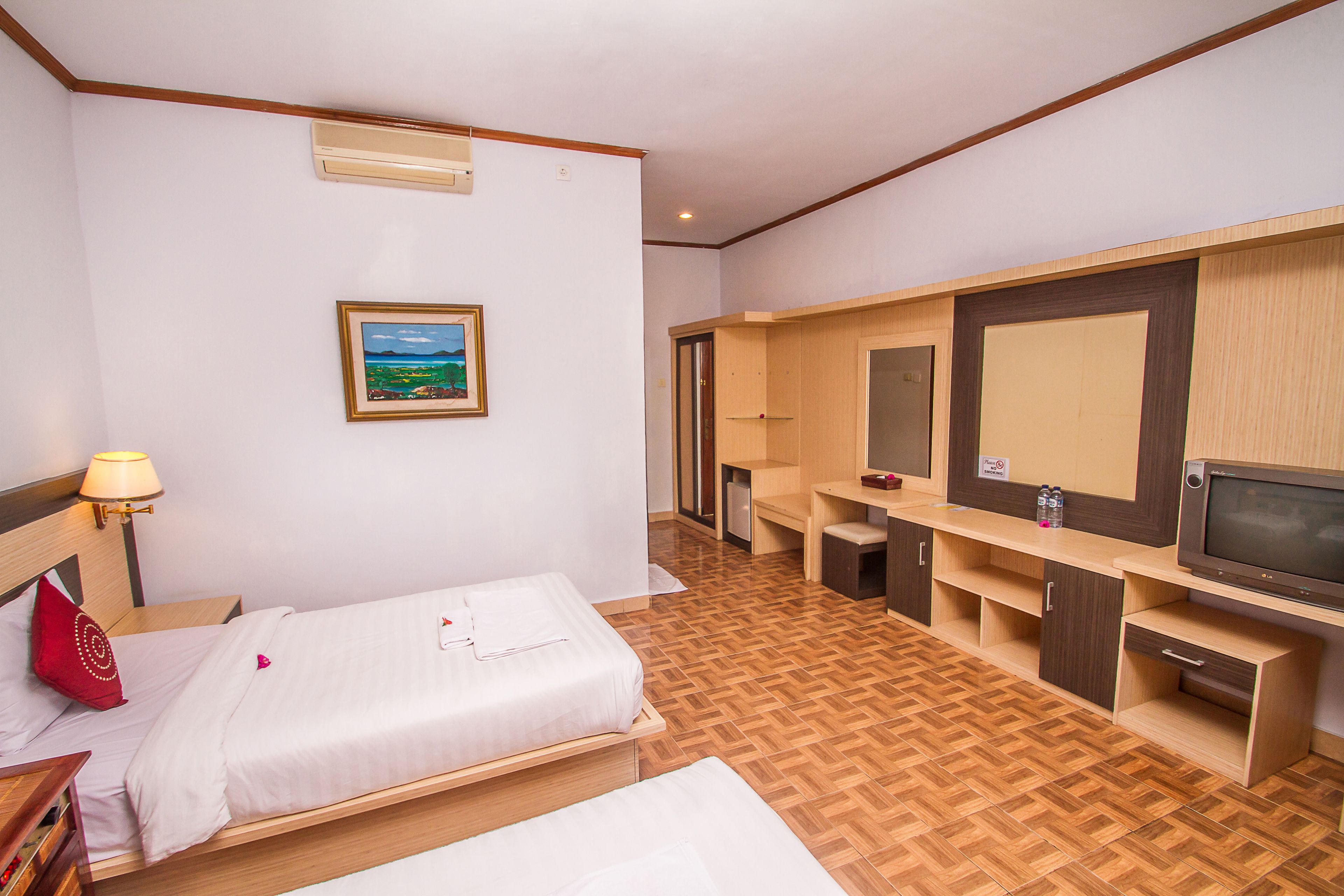 A hotel room with two beds, a desk, a TV, and a painting on the wall.