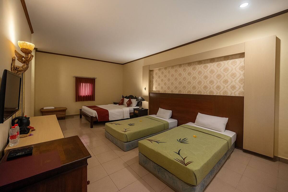 A hotel room with two beds, a desk, a television, and a mirror.