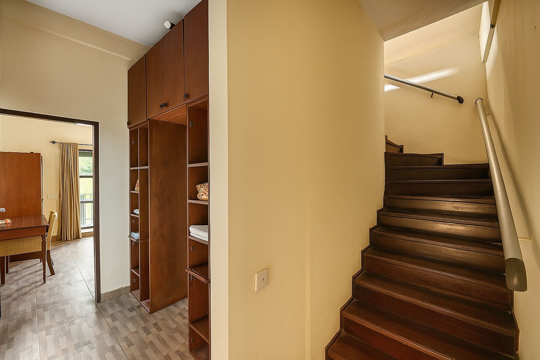 A staircase with wooden steps and a metal handrail, leading to an upper floor.