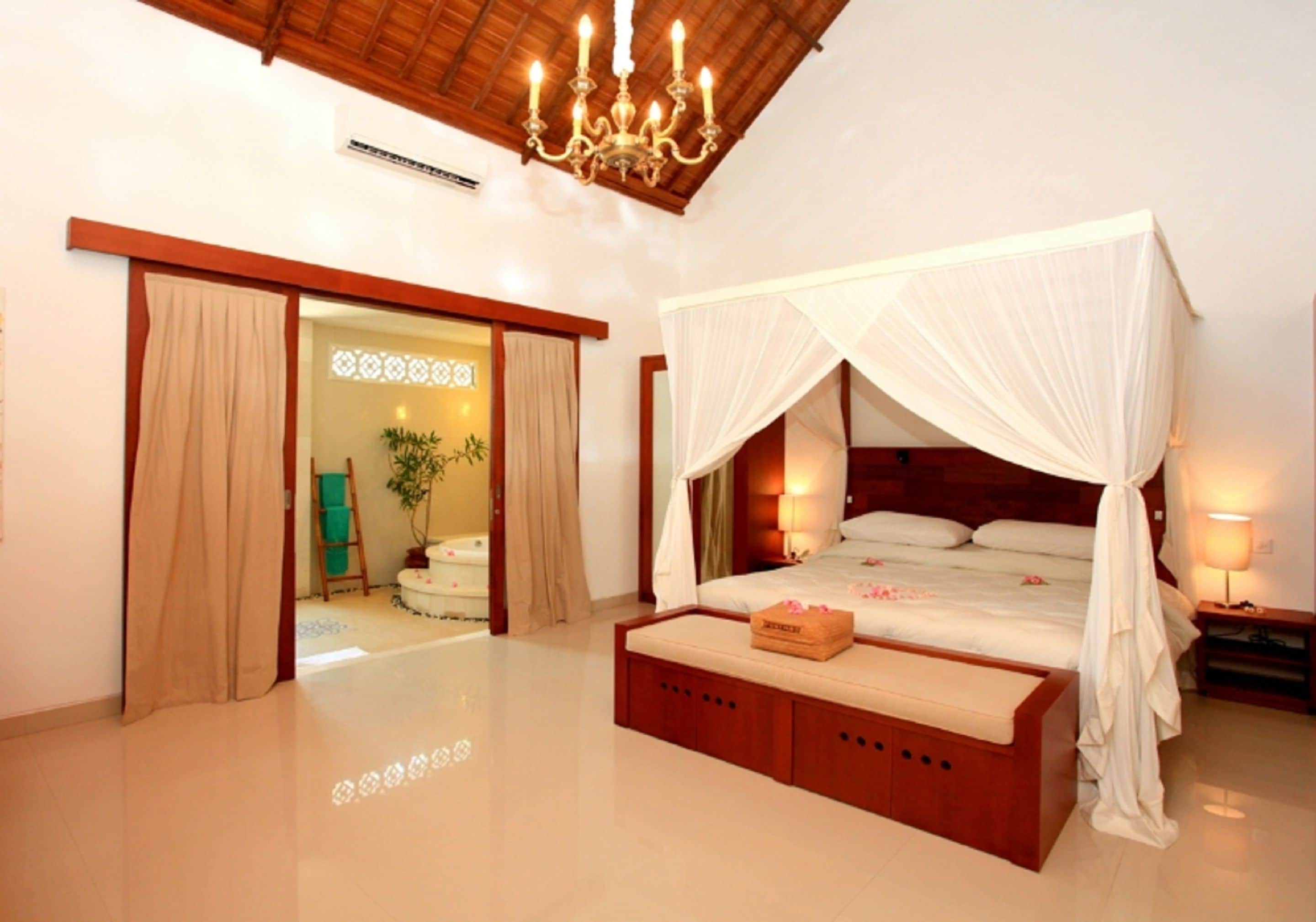 A spacious bedroom with a large bed, a canopy, and a wooden bench.