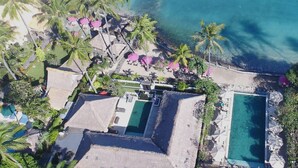 Vista aérea de un resort con varias piscinas, palmeras y sombrillas de playa.