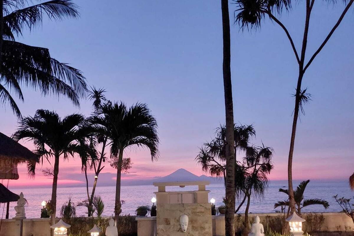 A pool with a view of the ocean and a mountain at sunset.