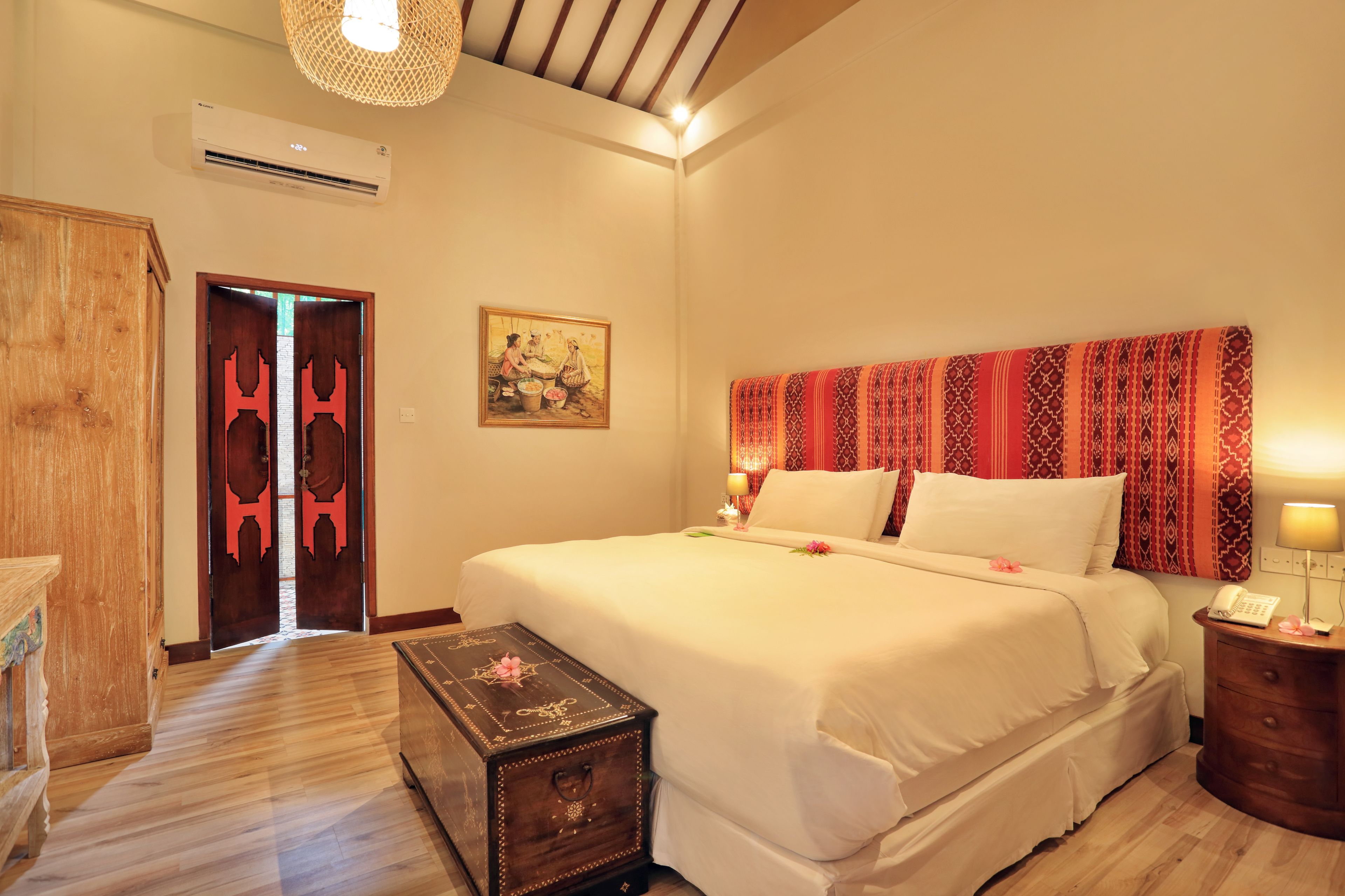Une chambre d’hôtel avec un grand lit, une armoire en bois, une petite table et un tableau au mur.