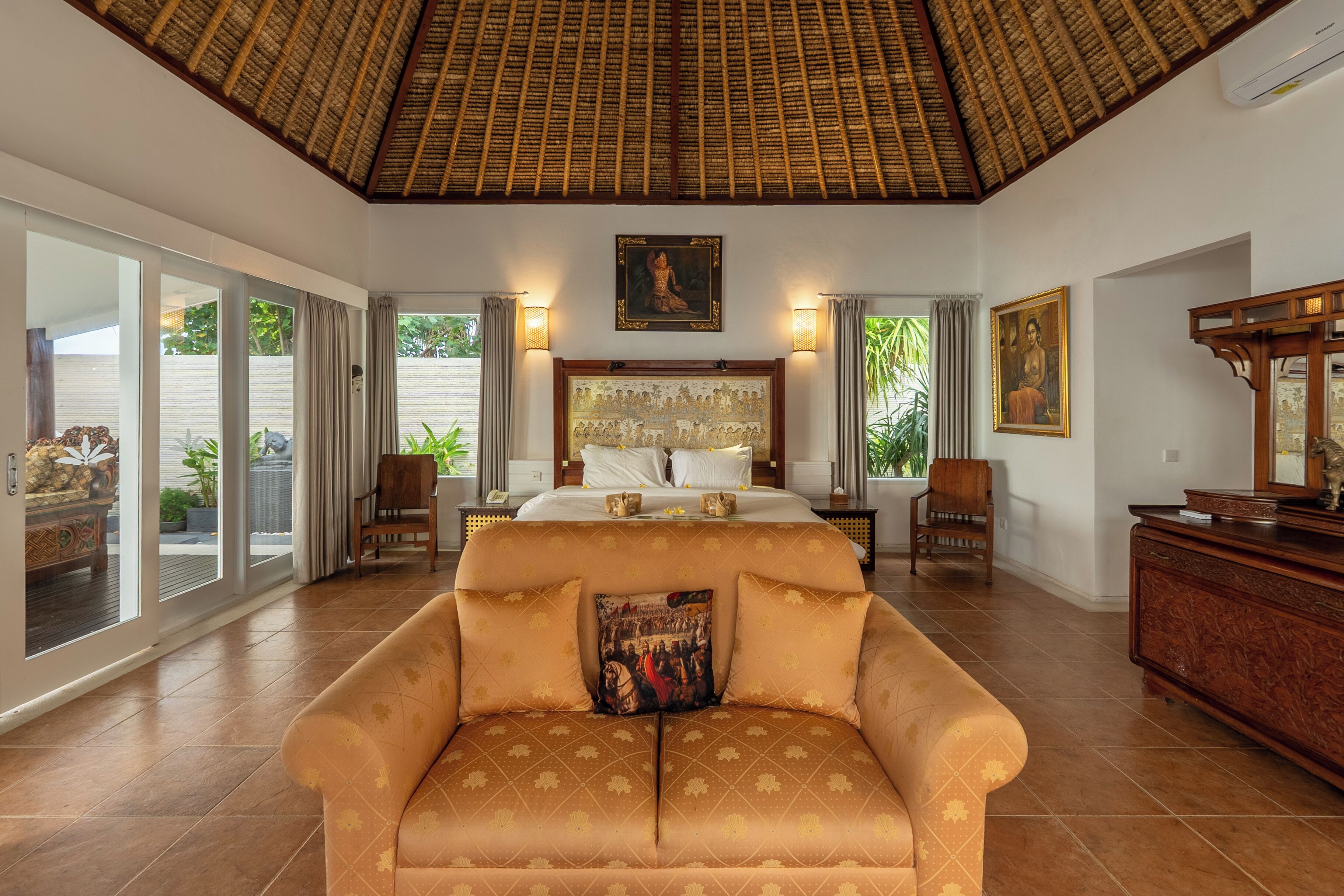 A spacious bedroom with a large bed, a sofa, and a dining area.