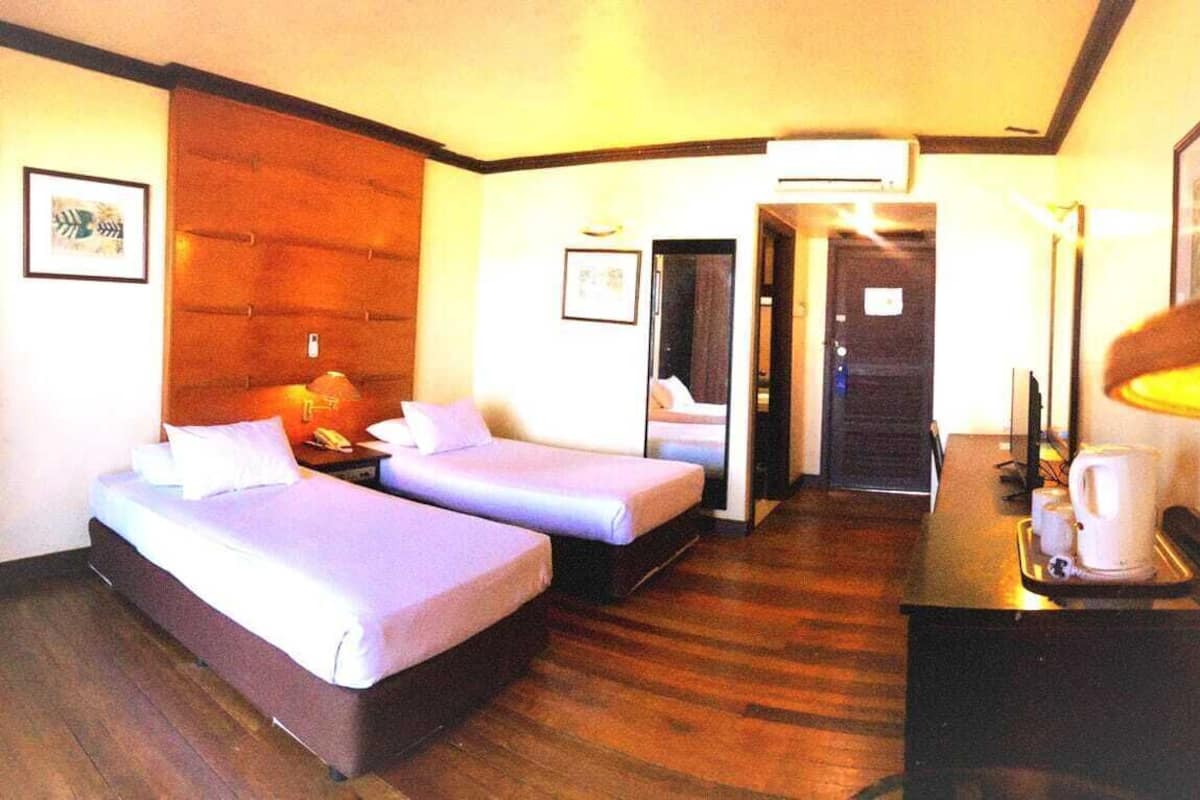 A hotel room with two beds, a desk with a lamp, a coffee maker, and framed pictures on the walls.