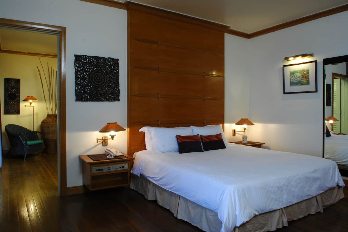 A neatly arranged hotel room with a large bed, two bedside tables, a chair, and a wall-mounted artwork.