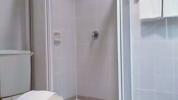 A bathroom with a shower, toilet, and a towel rack.