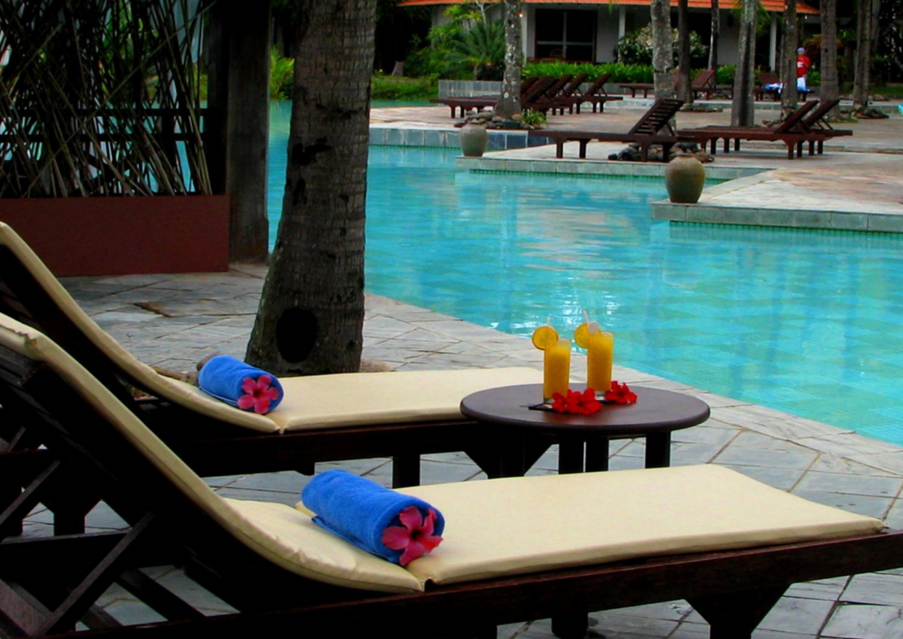A poolside area with lounge chairs and a table with drinks.