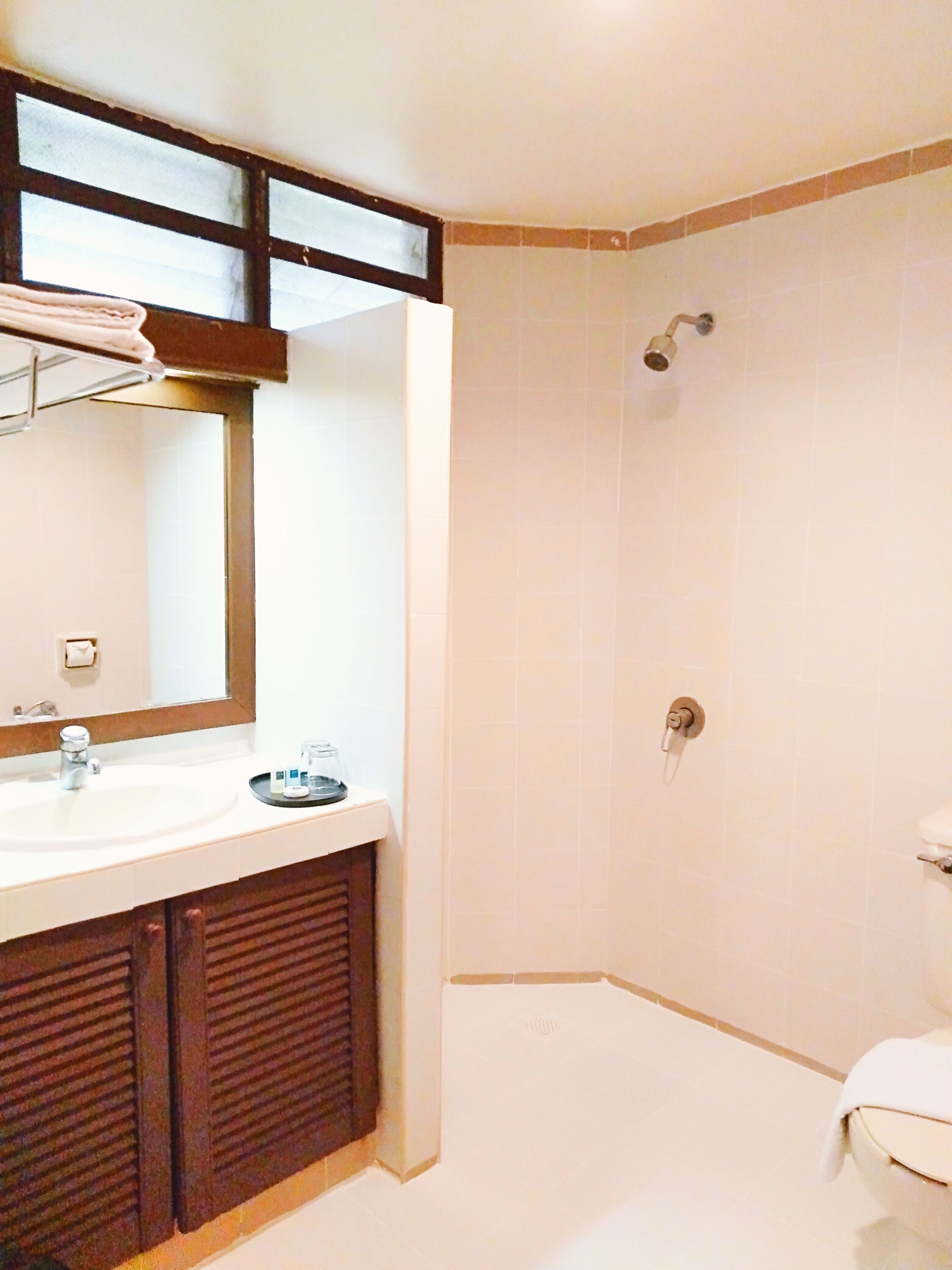 Un baño con lavamanos, espejo y ducha blancos.