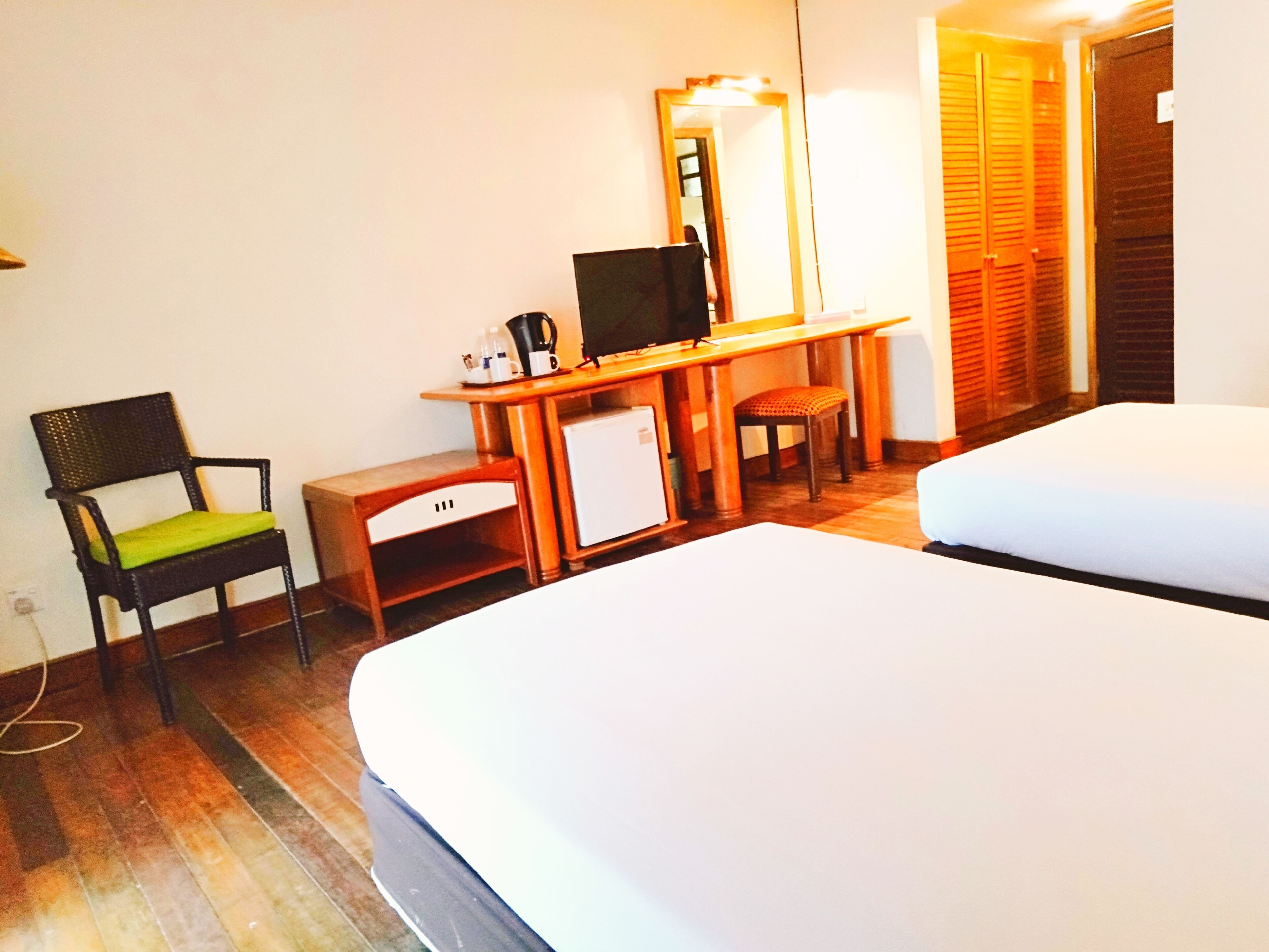 A hotel room with a bed, a desk with a computer, a chair, and a small refrigerator.