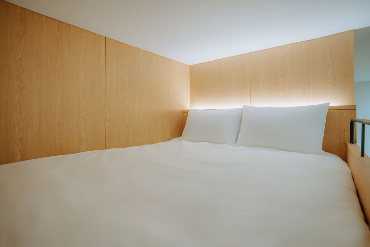A hotel room with a large bed, wooden headboard, and a nightstand.
