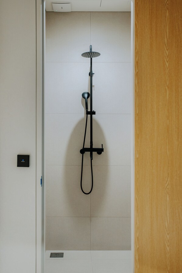 Een douche met een handdouche en een bedieningspaneel aan de muur.