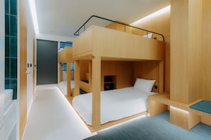Een moderne, compacte kamer met een stapelbed, een bureau en een klein zithoekje.