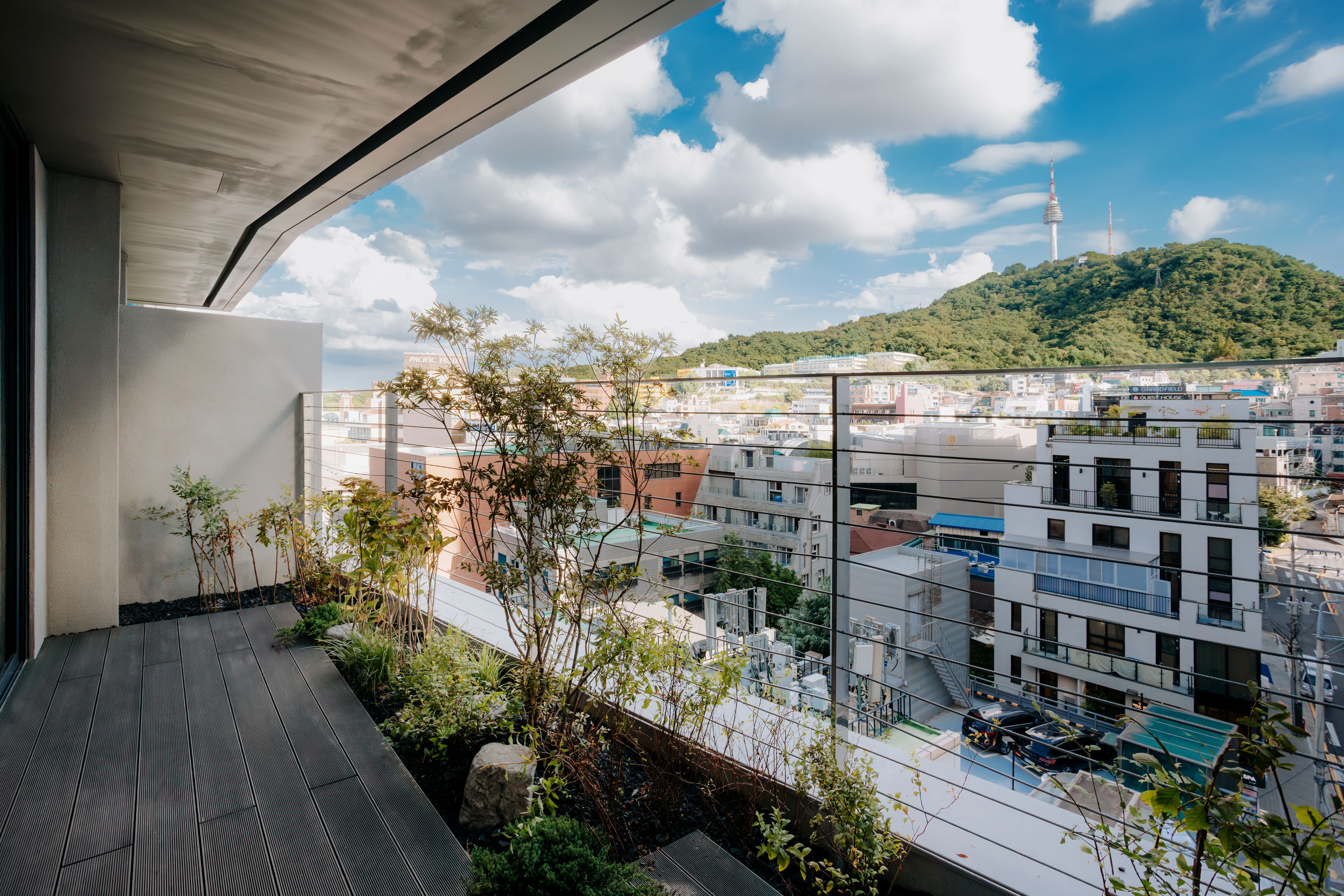 Un balcon offrant une vue sur le paysage urbain, avec des bâtiments et une colline surmontée d’une tour.