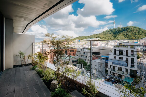 A balcony with a view of a cityscape, including buildings and a hill with a tower.