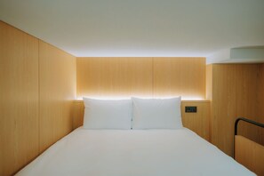 Ein Hotelzimmer mit einem Bett, Holzwänden und einem Kopfteil mit integrierter Beleuchtung.