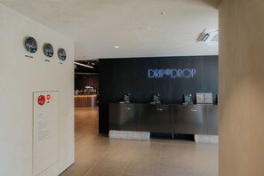Een receptiebalie met een neonbord, een veiligheidsposter met een brandkraan en klokken die verschillende steden aangeven.