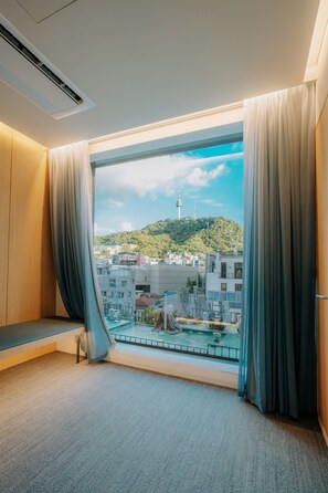 Ein Hotelzimmer mit großem Fenster, Stadtblick und Balkon.