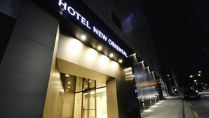 L’entrée d’un hôtel au design moderne, avec une enseigne bien visible sur laquelle on peut lire : « HÔTEL NEW OREGONAL ».