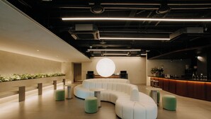A modern lounge area with a curved seating arrangement, a central circular light feature, and a bar counter. - HOTEL DRIP&DROP Myeongdong Central (Seoul)