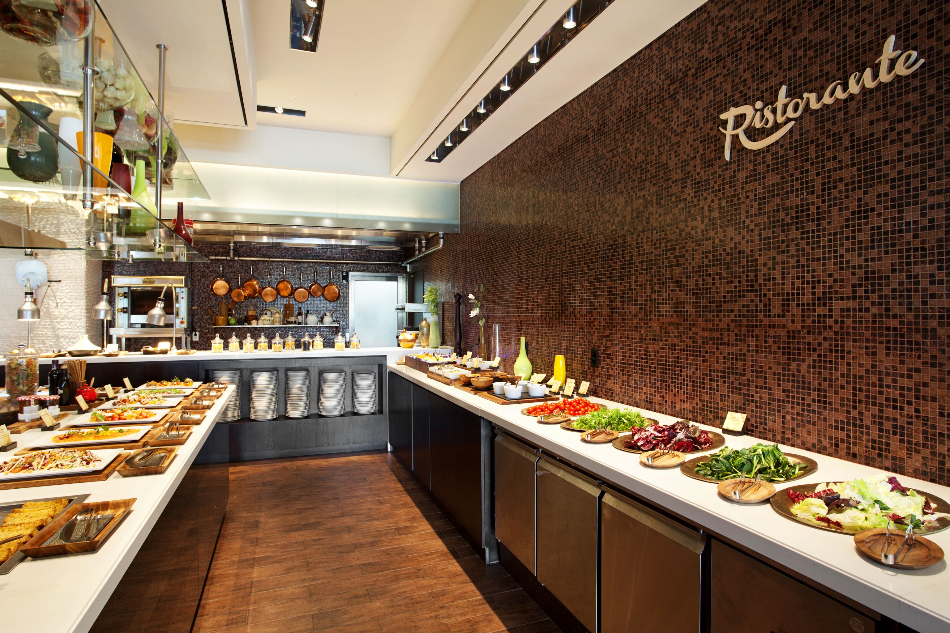 Un buffet proposant une variété de plats, avec un mur en briques sur lequel est inscrit le mot « Ristorante ».