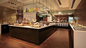 En buffet med et udvalg af mad og drikkevarer, et glasgelænder og en murstensvæg i baggrunden.