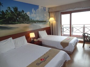 A hotel room with two beds, a mural of a beach, a balcony with a chair, and a lamp. - Ocean Grand Hotel Jeju (Jeju City)